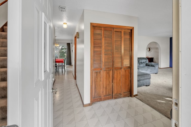 hallway with a textured ceiling and light colored carpet