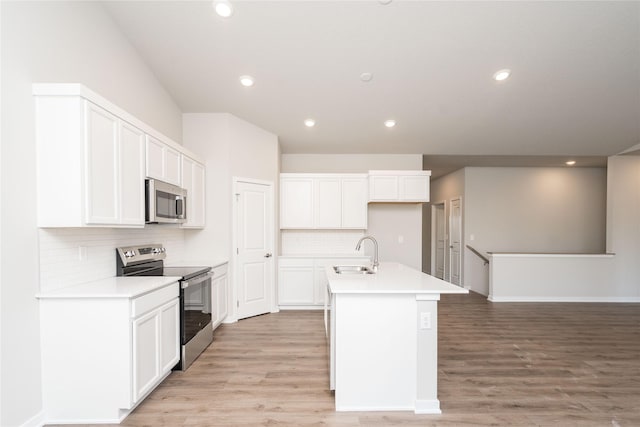 kitchen with a center island with sink, sink, light wood-type flooring, and stainless steel appliances