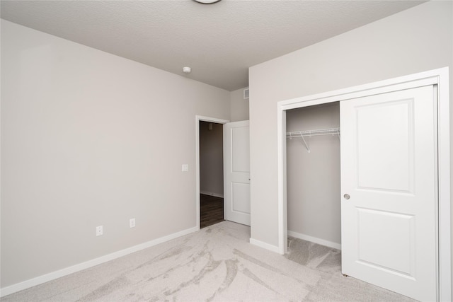 unfurnished bedroom with light carpet, a closet, and a textured ceiling