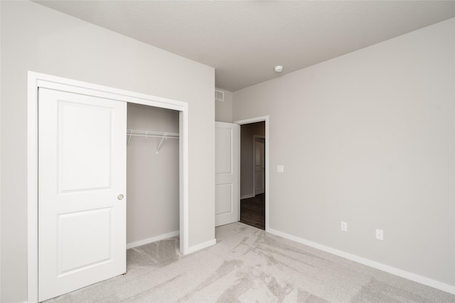 unfurnished bedroom featuring light carpet and a closet