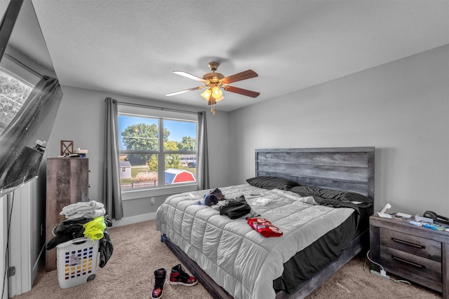 carpeted bedroom with ceiling fan and a textured ceiling