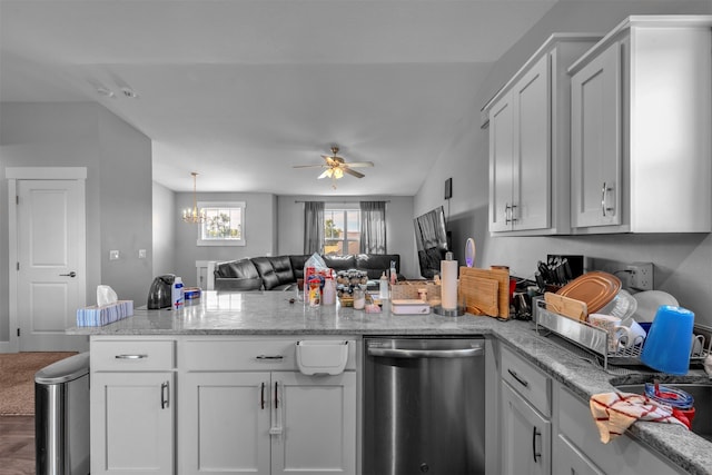 kitchen with ceiling fan with notable chandelier, dishwasher, vaulted ceiling, and white cabinetry