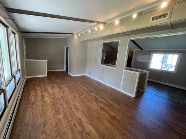 unfurnished living room featuring baseboard heating, beam ceiling, and dark hardwood / wood-style flooring