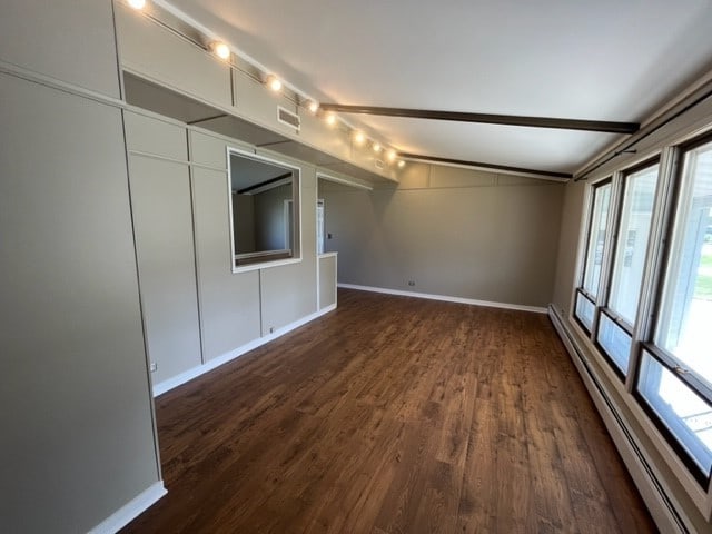 spare room with lofted ceiling with beams, a baseboard radiator, and dark wood-type flooring