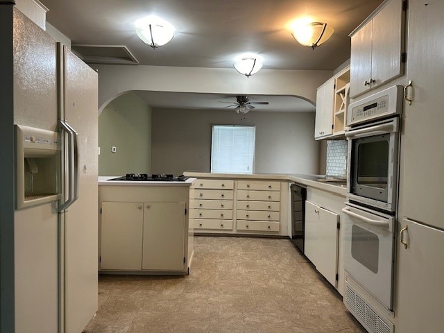 kitchen with stainless steel double oven, dishwasher, white fridge with ice dispenser, kitchen peninsula, and ceiling fan