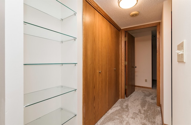 corridor featuring light colored carpet and a textured ceiling