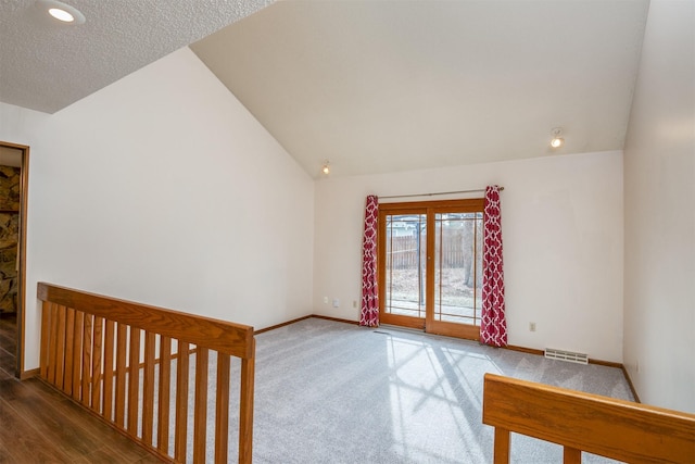 empty room featuring vaulted ceiling and dark colored carpet