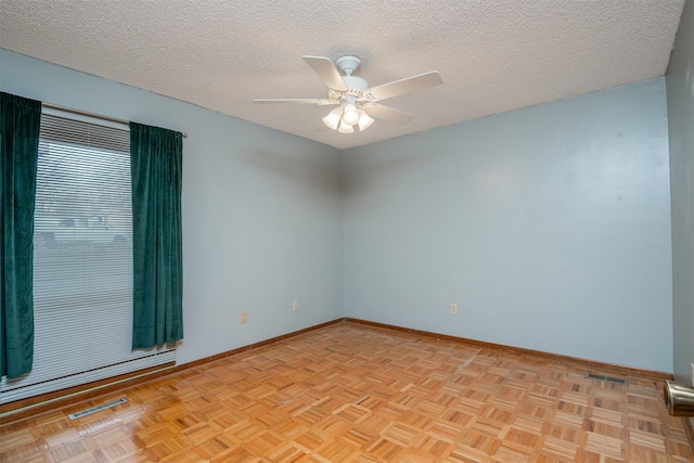 spare room featuring ceiling fan, light parquet flooring, and a textured ceiling