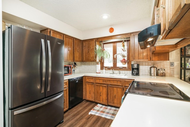 kitchen featuring tasteful backsplash, dishwasher, sink, stainless steel fridge, and stove