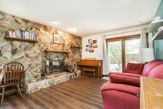 living room with a stone fireplace and dark hardwood / wood-style flooring