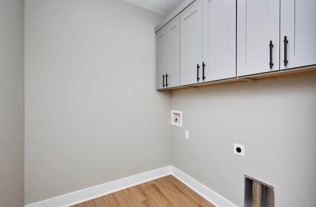 washroom with electric dryer hookup, hookup for a washing machine, cabinets, and light hardwood / wood-style floors