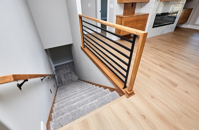 stairs with a tiled fireplace and wood-type flooring