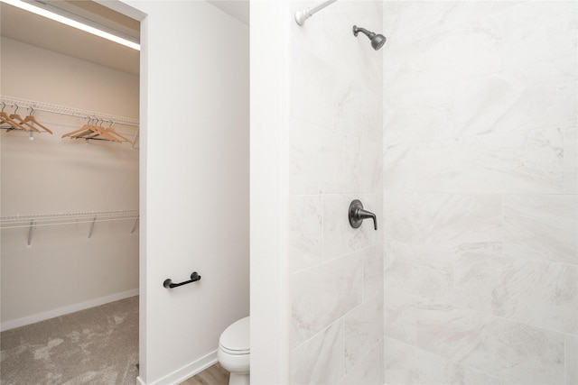 bathroom featuring tiled shower and toilet