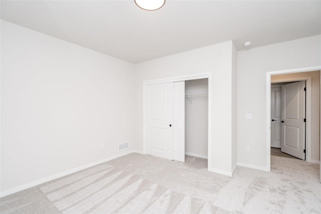 unfurnished bedroom featuring light carpet and a closet