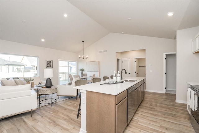 kitchen featuring light hardwood / wood-style floors, lofted ceiling, sink, and an island with sink