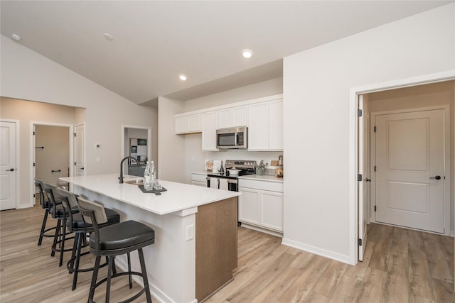 kitchen with a center island with sink, white cabinets, light wood-type flooring, and appliances with stainless steel finishes