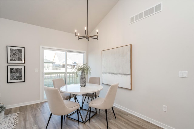 dining area featuring high vaulted ceiling, wood-type flooring, and a notable chandelier