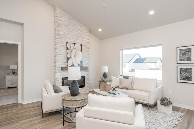 living room with a fireplace, hardwood / wood-style floors, and vaulted ceiling