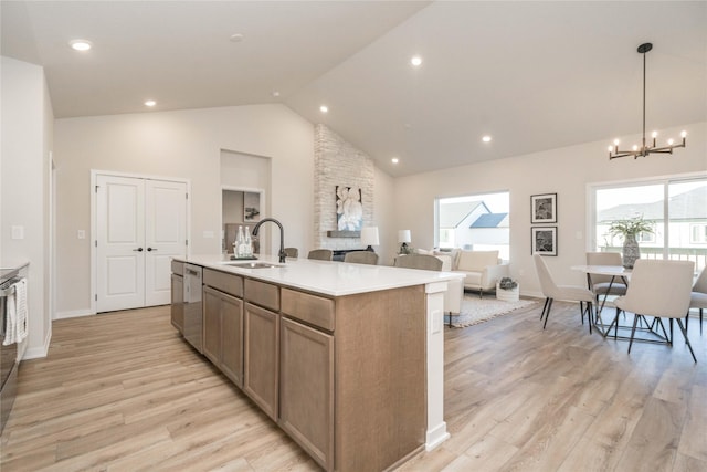 kitchen featuring hanging light fixtures, sink, an island with sink, and light hardwood / wood-style flooring