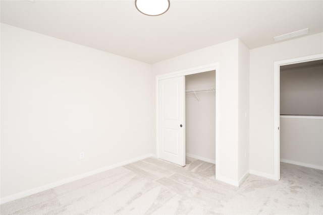 unfurnished bedroom featuring light carpet and a closet