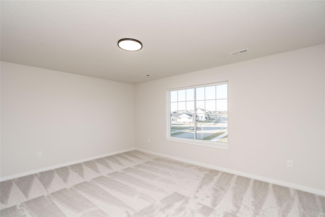 unfurnished room with light carpet and a textured ceiling