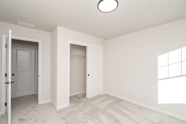 unfurnished bedroom featuring light colored carpet, a textured ceiling, and a closet