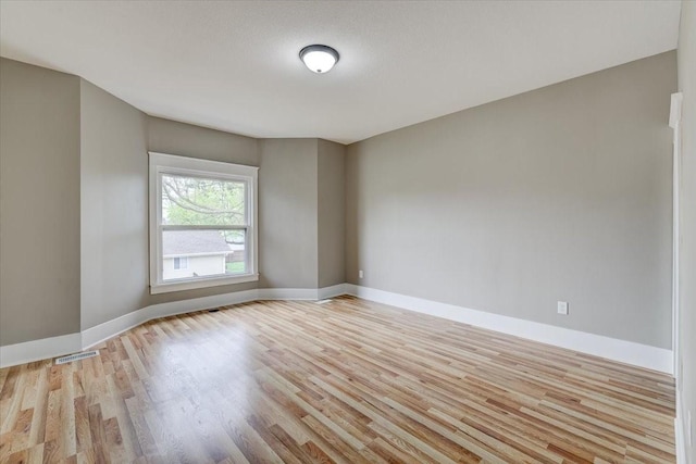 spare room featuring light hardwood / wood-style floors and a textured ceiling