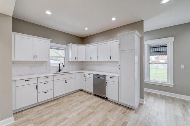 kitchen featuring dishwasher, sink, white cabinets, and light wood-type flooring