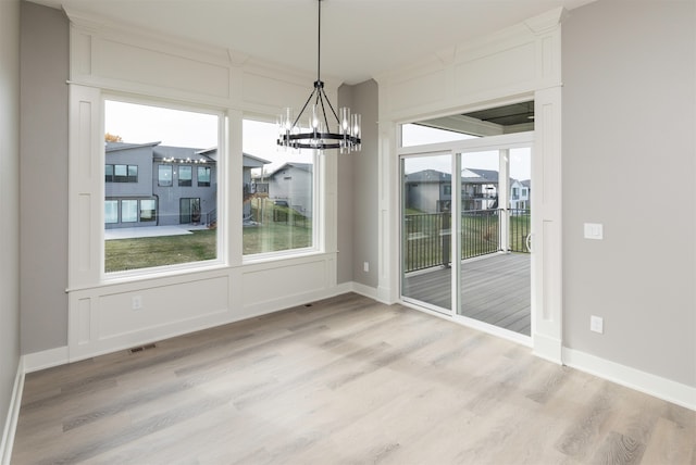 unfurnished dining area featuring light hardwood / wood-style floors and a chandelier