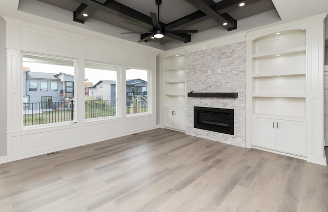 unfurnished living room featuring a fireplace, ceiling fan, light hardwood / wood-style floors, beamed ceiling, and built in shelves