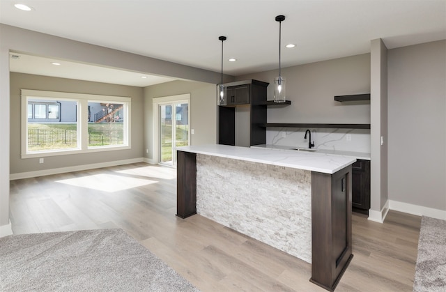 kitchen featuring sink, light stone countertops, light hardwood / wood-style flooring, and pendant lighting