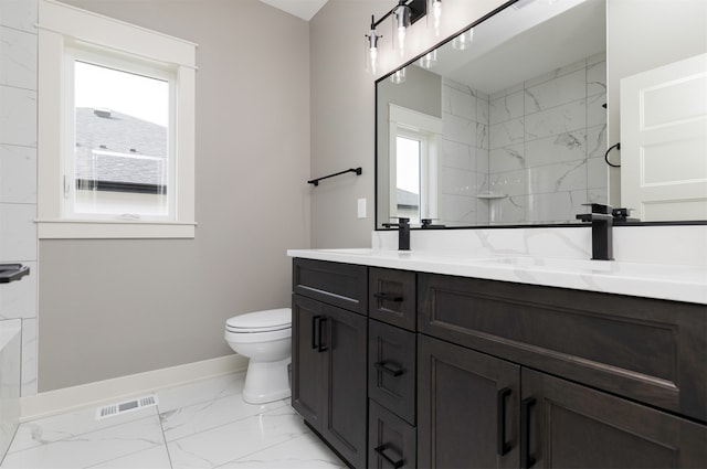 bathroom featuring vanity, tiled shower, toilet, and plenty of natural light