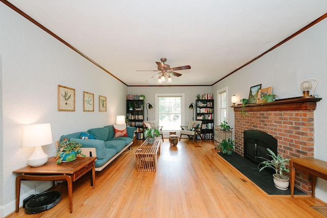 living room with crown molding, ceiling fan, a fireplace, and light hardwood / wood-style floors