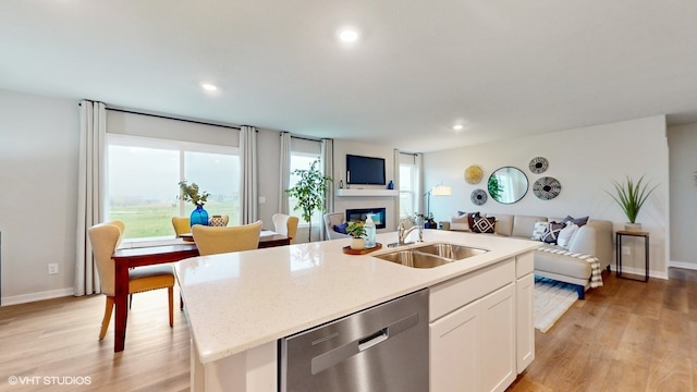 kitchen featuring sink, light hardwood / wood-style flooring, stainless steel dishwasher, an island with sink, and white cabinets