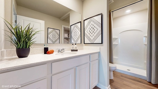 bathroom with walk in shower, toilet, vanity, and hardwood / wood-style flooring