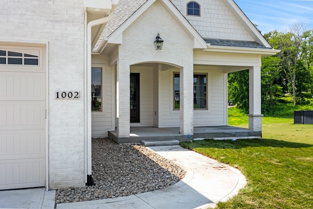 entrance to property with a yard, covered porch, and a garage