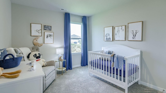 carpeted bedroom featuring baseboards, visible vents, and a nursery area