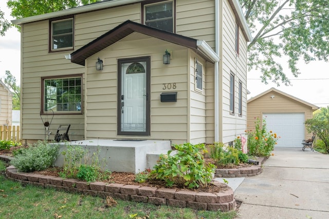 view of front of house with an outbuilding, concrete driveway, fence, and a detached garage