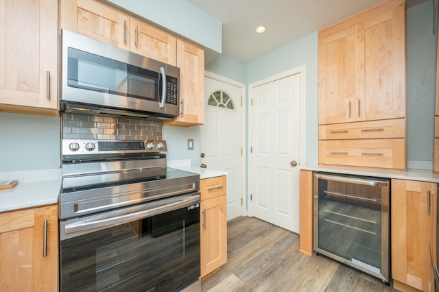 kitchen featuring light hardwood / wood-style floors, backsplash, stainless steel appliances, light brown cabinetry, and beverage cooler