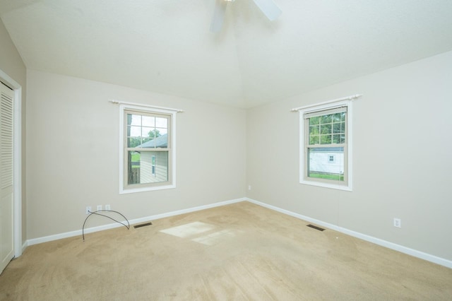 unfurnished room with visible vents, baseboards, light colored carpet, and a ceiling fan