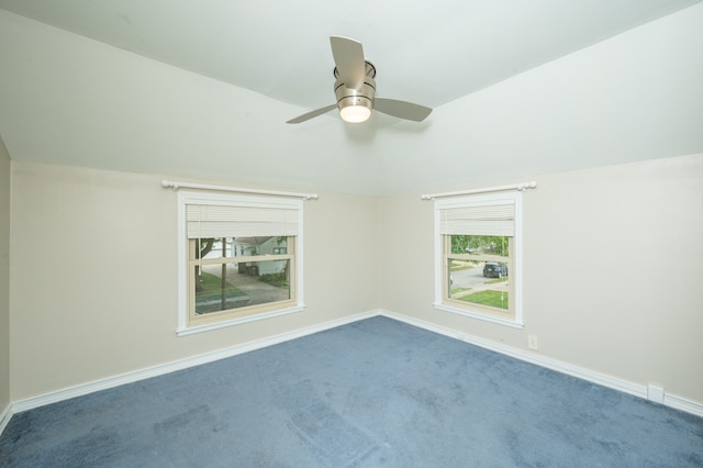 carpeted spare room with vaulted ceiling, ceiling fan, and plenty of natural light