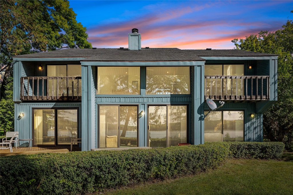 back house at dusk featuring a balcony