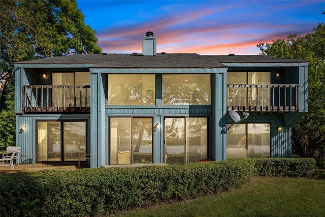 back house at dusk featuring a balcony