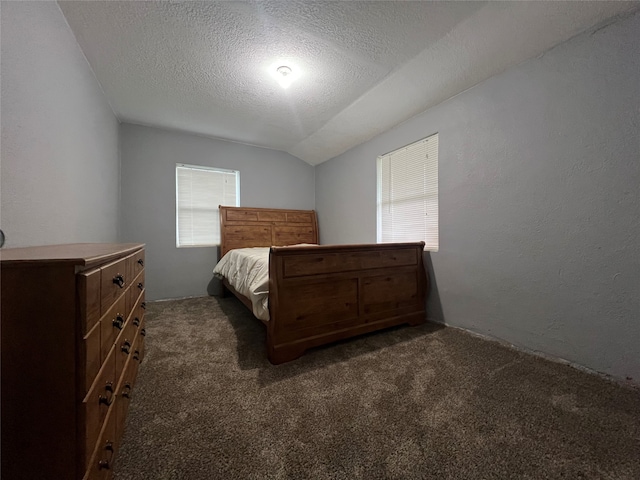 bedroom with a textured ceiling, vaulted ceiling, and dark carpet