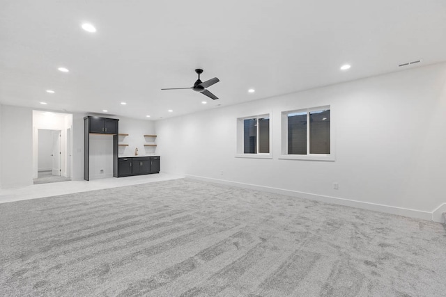 unfurnished living room featuring carpet flooring, sink, and ceiling fan