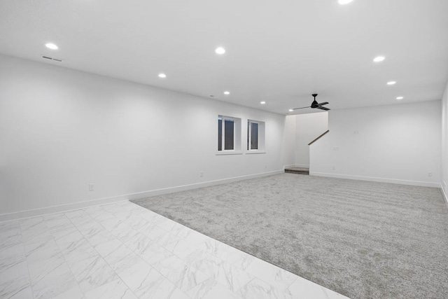 basement with ceiling fan and light colored carpet