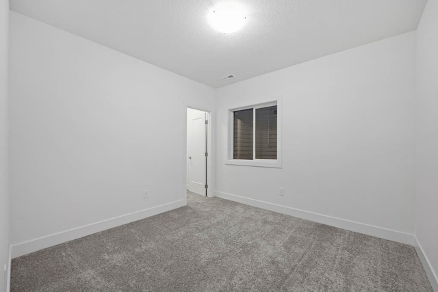 carpeted empty room featuring a textured ceiling