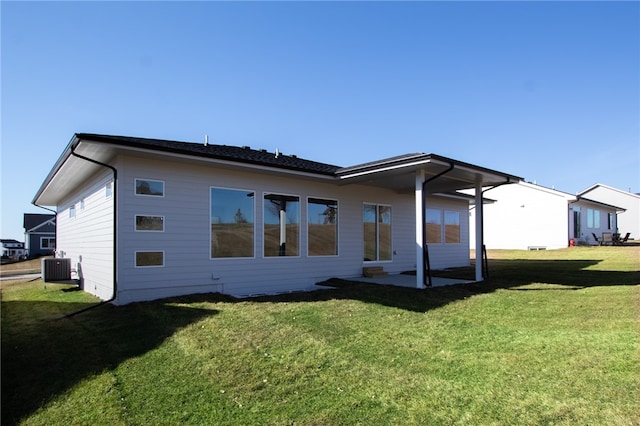 rear view of house featuring a lawn, central AC, and a patio area