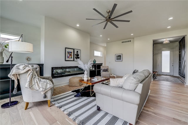 living room with ceiling fan and light hardwood / wood-style flooring