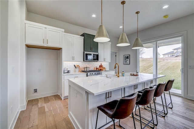 kitchen featuring white cabinets, a kitchen island with sink, stainless steel appliances, and a wealth of natural light